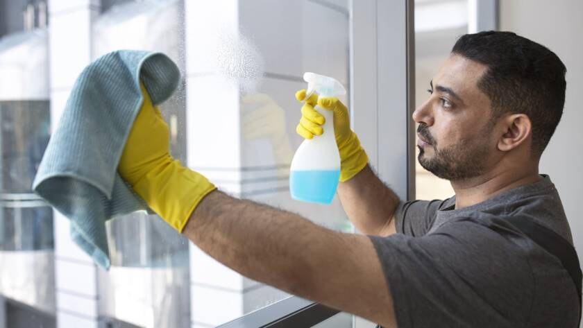 Employé qui nettoie une vitre avec un linge